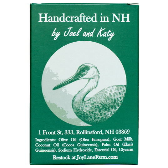 A green rectangular box with white text reading 'Handcrafted in NH by Joel and Katy' and a circular illustration of a heron. The box also includes the address Restock at JoyLaneFarm.