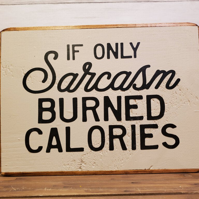 Wooden sign with humorous text 'If only sarcasm burned calories' on a wooden surface.