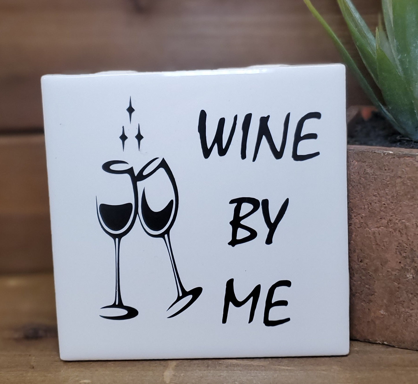 Decorative sign with 'Wine by Me' text and wine glass illustrations on a white background.