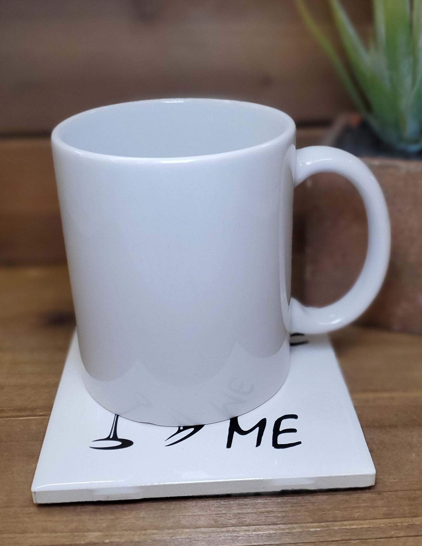 White mug on a coaster with 'I ❤️ ME' text on a wooden surface.