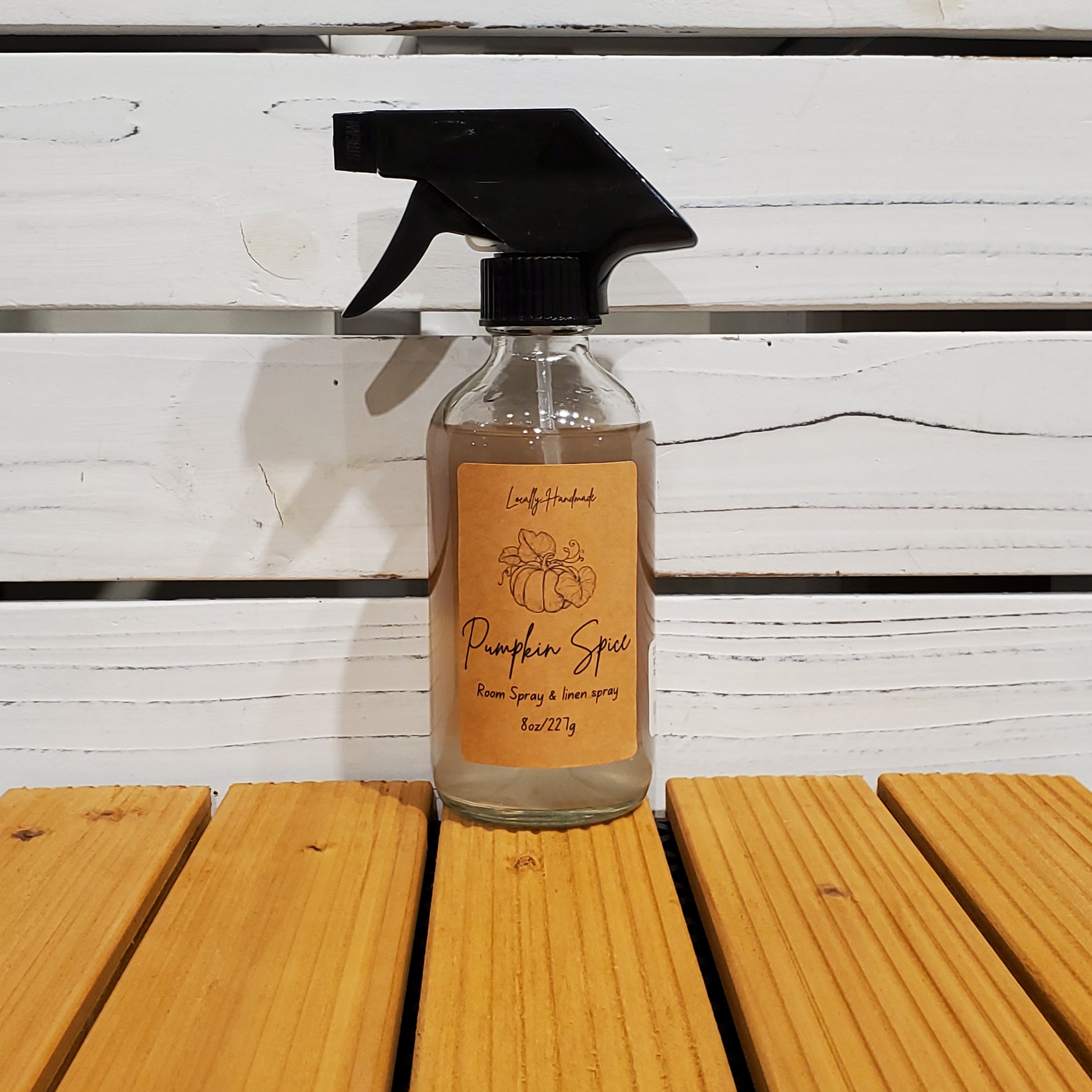 Bottle of pumpkin spice spray on a wooden surface with a white background