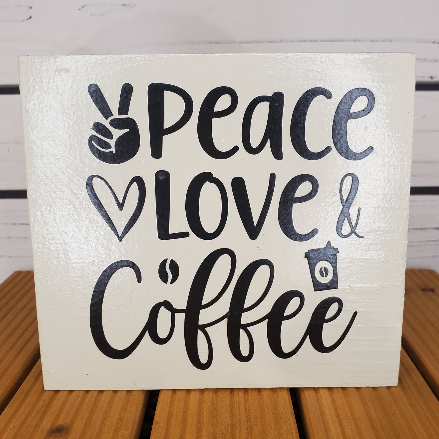 Wooden sign with 'Peace Love Coffee' text on a wooden surface