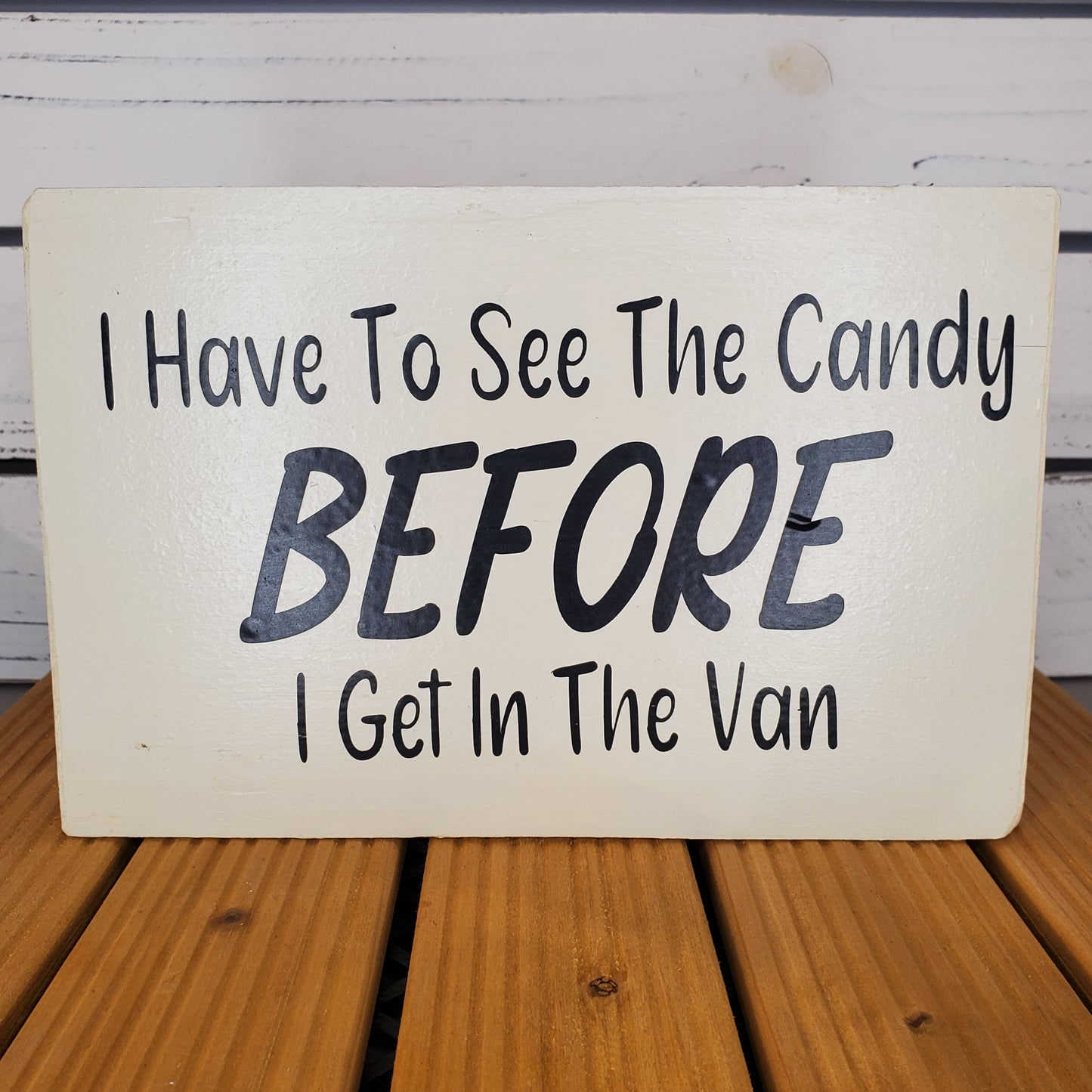 Handwritten sign on a wooden surface with text 'I Have To See The Candy Before I Get In The Van'.