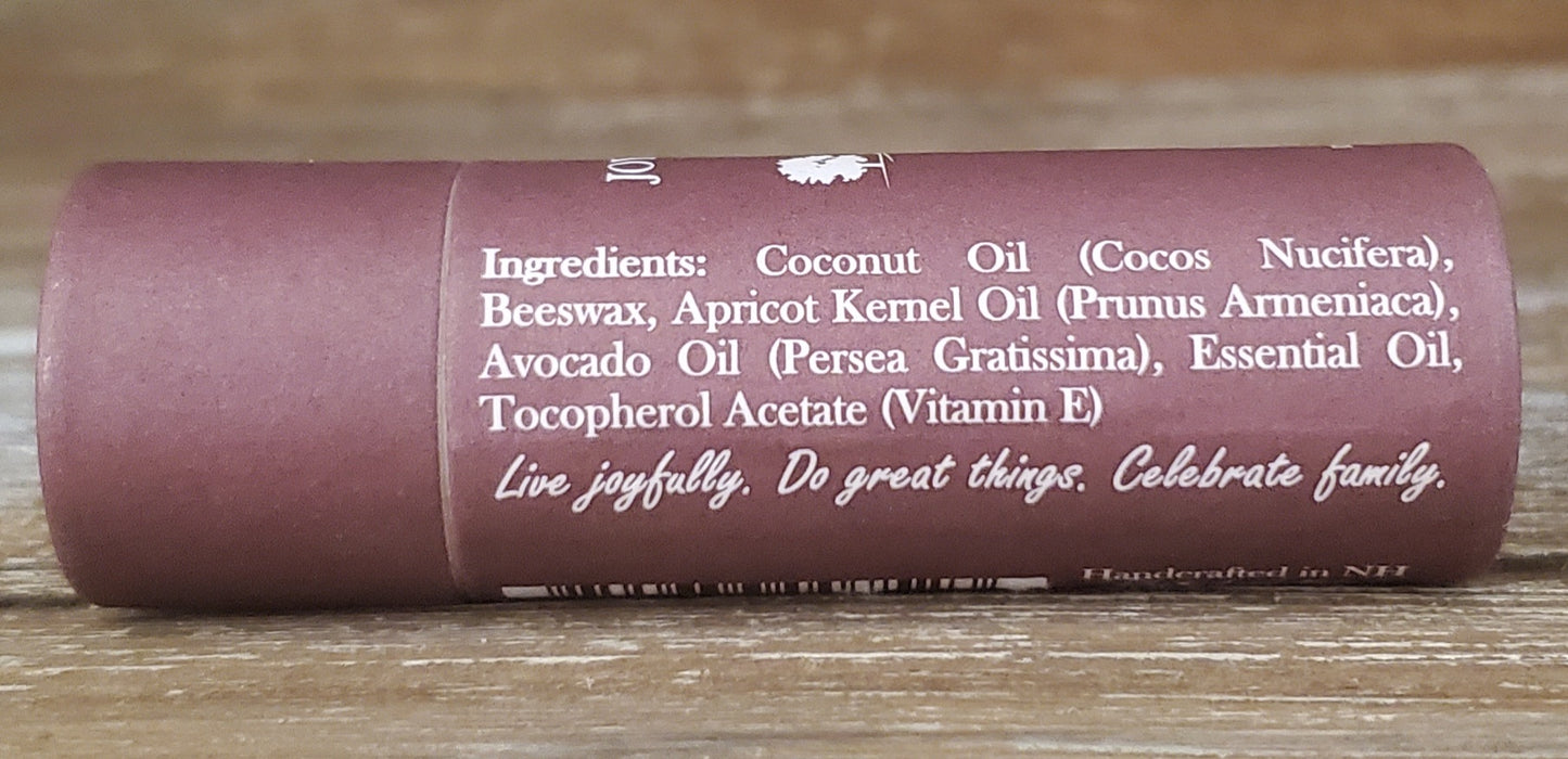 Roll of lip balm with ingredients listed on a wooden surface
