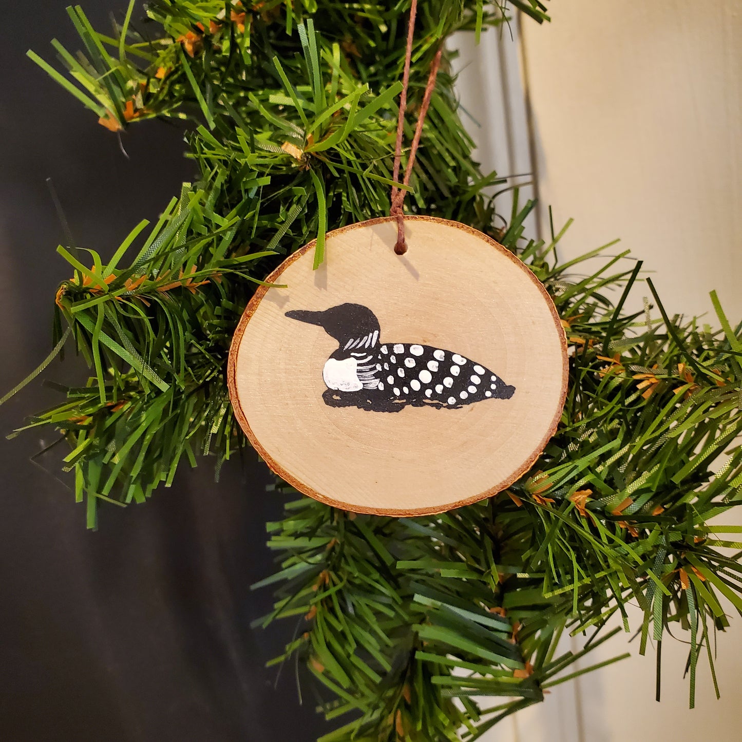 Wooden ornament with a feather design on a Christmas tree.