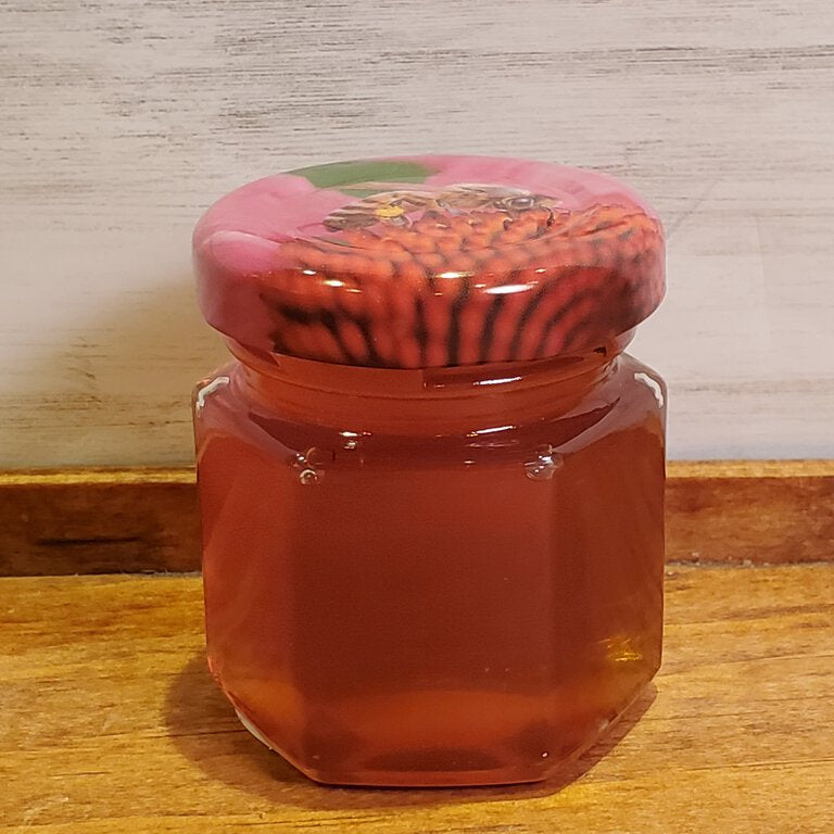 Clear glass jar with a red and black patterned lid on a wooden surface.