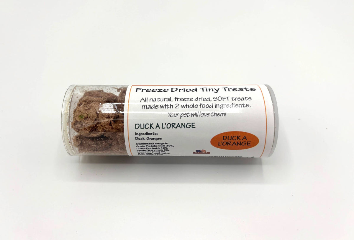 A clear plastic tube containing freeze dried duck orange pet treats, with a white label that reads 'Freeze Dried Tiny Treats' and 'DUCK A LORANGE'.