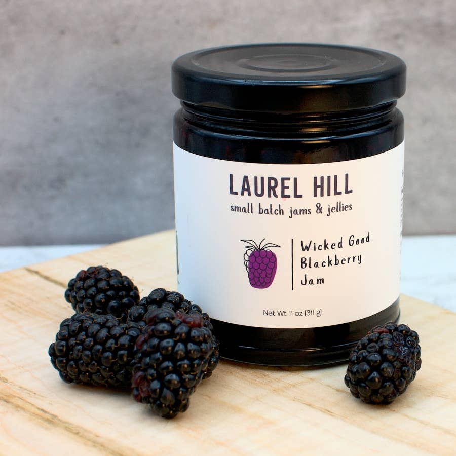 Jar of Laurel Hill Wicked Good Blackberry Jam with blackberries on a wooden board
