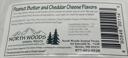 Close-up of a North Woods Animal Treats label showing Peanut Butter and Cheddar Cheese Flavors, with ingredients, guaranteed analysis, address, phone number, and a barcode.