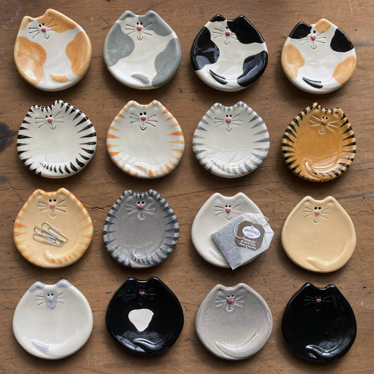 Collection of cat-shaped ceramic plates on a wooden surface