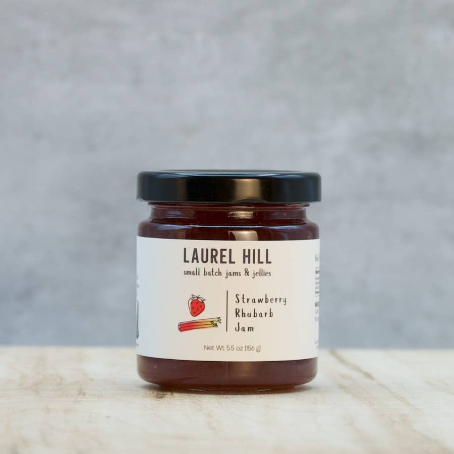 Jar of Laurel Hill Strawberry Rhubarb Jam on a wooden surface with a gray background