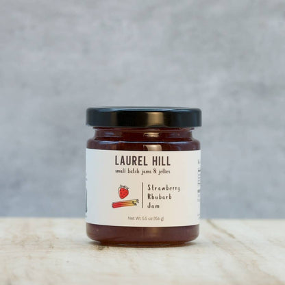 Jar of Laurel Hill Strawberry Rhubarb Jam on a wooden surface with a gray background