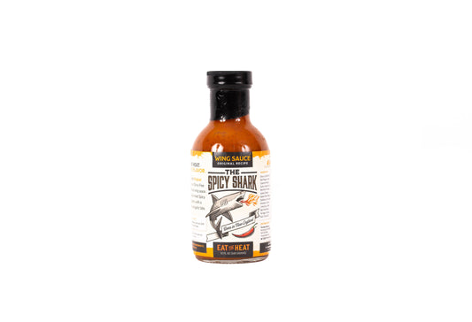 A bottle of Wing Sauce Hot Honey Sauce, specifically 'The Spicy Shark' flavor, featuring a black cap and a white label with a shark illustration, set against a plain white background.