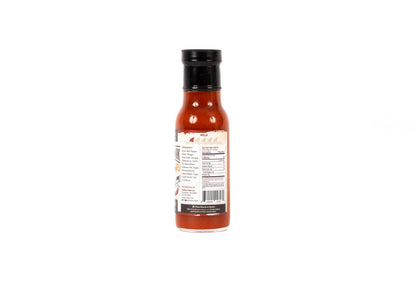 A bottle of hot sauce shown from the back, featuring a black cap and a white label with red and black text, set against a plain white background.