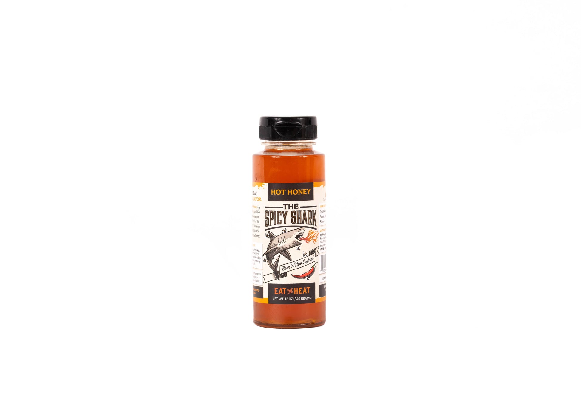 A bottle of 'The Spicy Shark' hot sauce by Hot Honey, featuring a black cap and a label with a shark illustration, set against a plain white background.