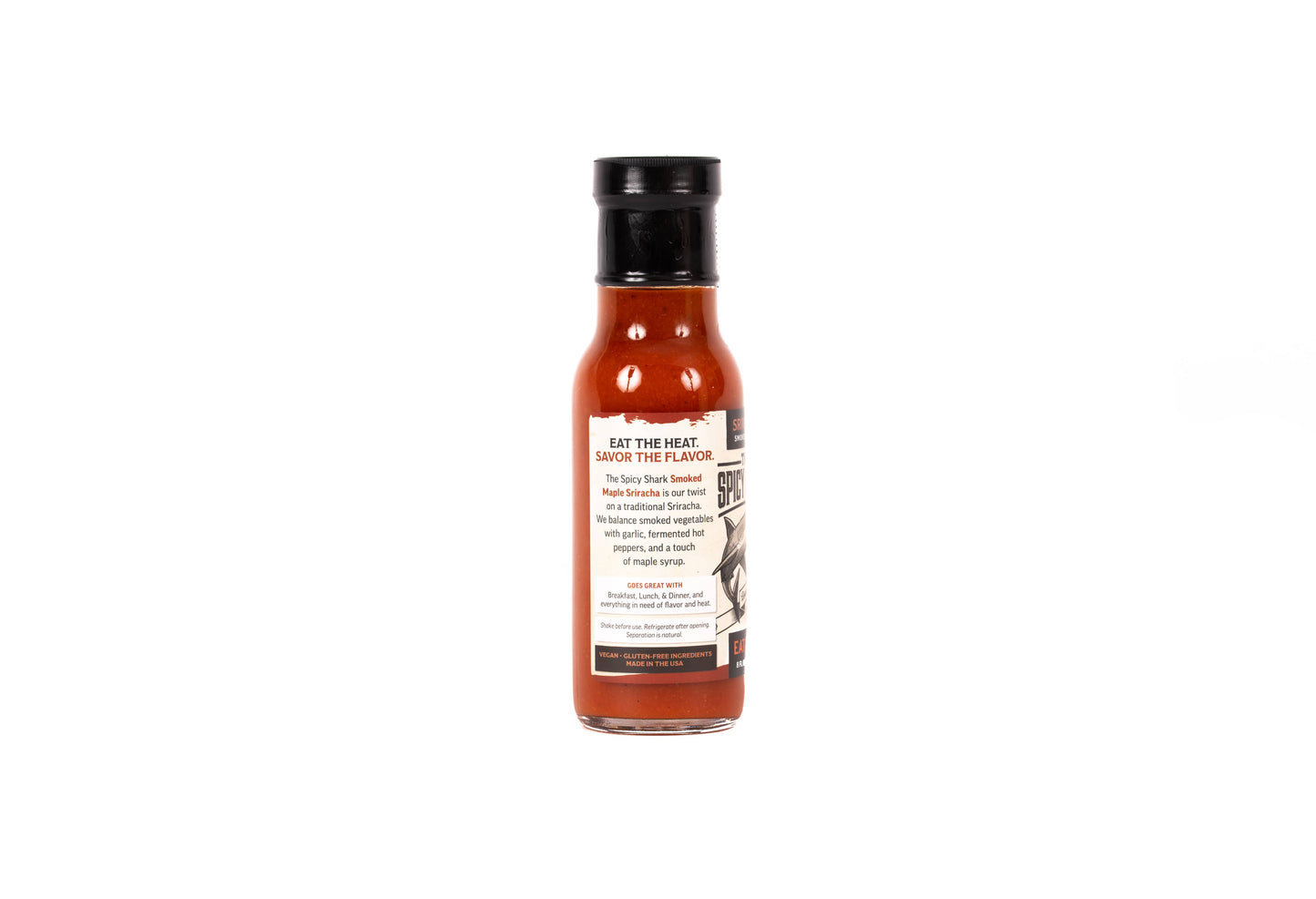 A small glass bottle of hot sauce with reddish-brown sauce inside, a black cap, and a cream label that reads 'EAT THE HEAT SAUCE THE FLAVOR' on a plain white background.