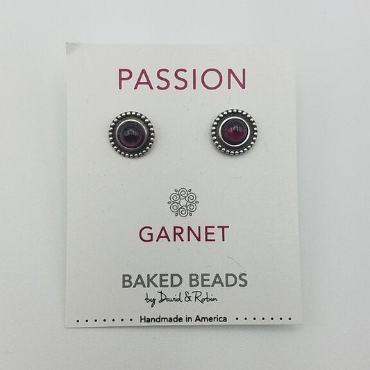 A pair of garnet power stone stud earrings displayed on a white card with 'PASSION GARNET' written on it, under the brand name 'BAKED BEADS by Joshua & Rachel'.