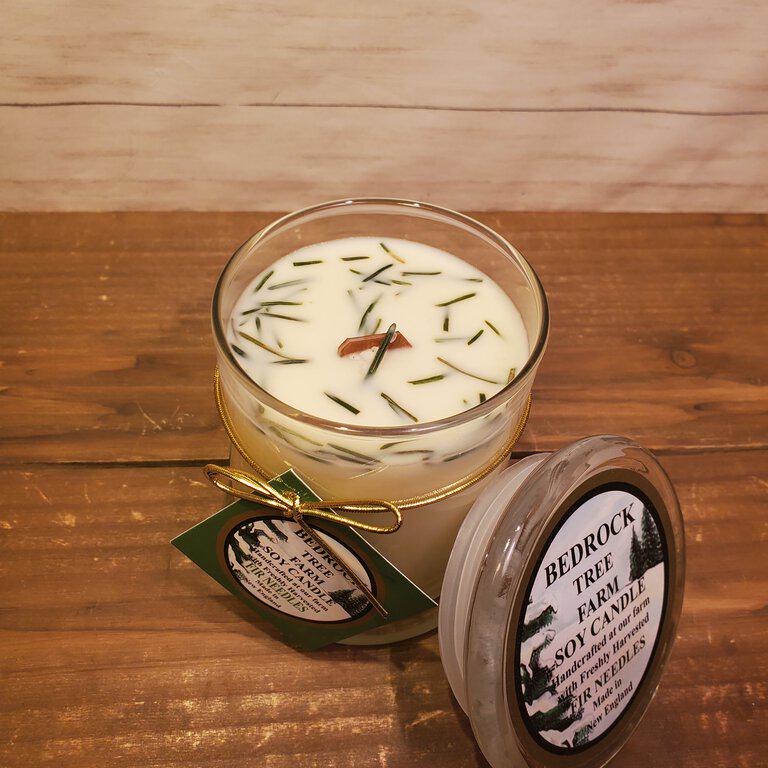 A soy wax candle in a clear glass jar with a Fir Natural Libbey Status Jar label, featuring a natural woodsy fragrance.