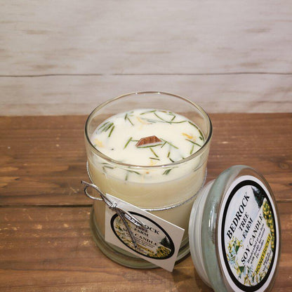 A soy wax candle with a floral fragrance, contained in a clear glass jar with a lid, placed on a wooden surface. The candle is labeled with the brand 'Honeysuckle Libbey'.