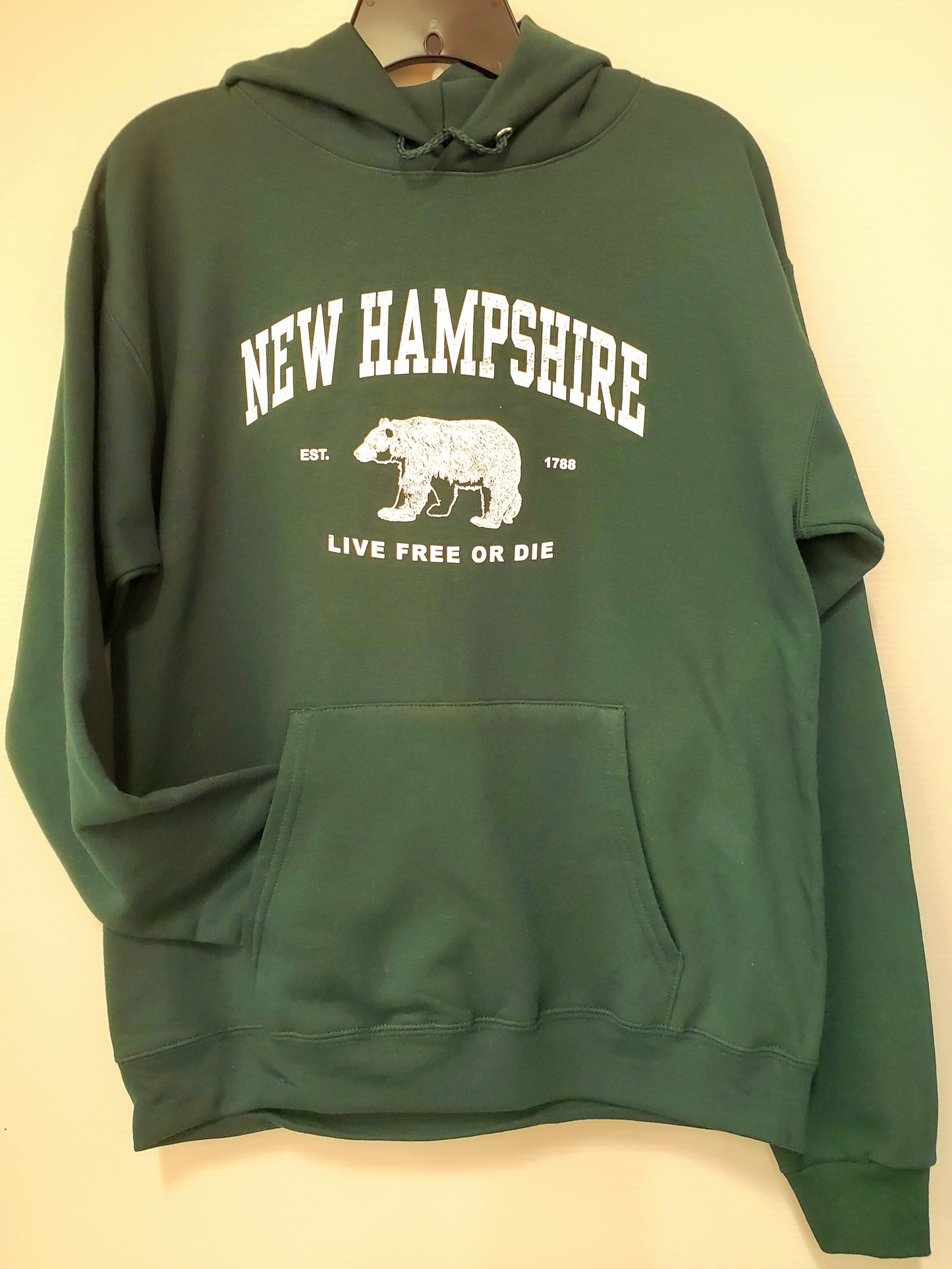 Green hoodie with 'New Hampshire' and bear graphic on a beige background