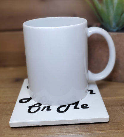 White mug on a coaster with text on a wooden surface