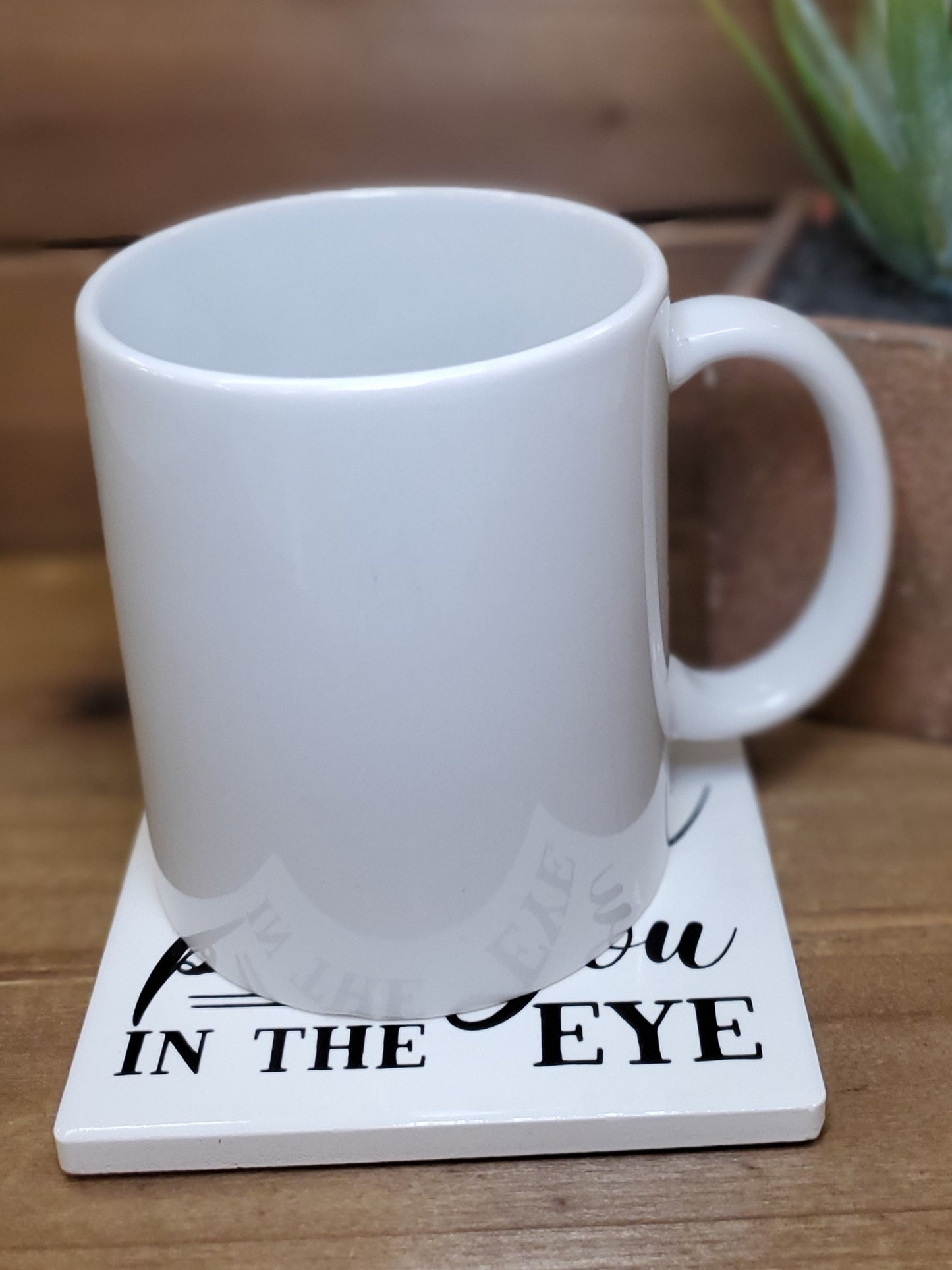 White mug on a coaster with text on a wooden surface