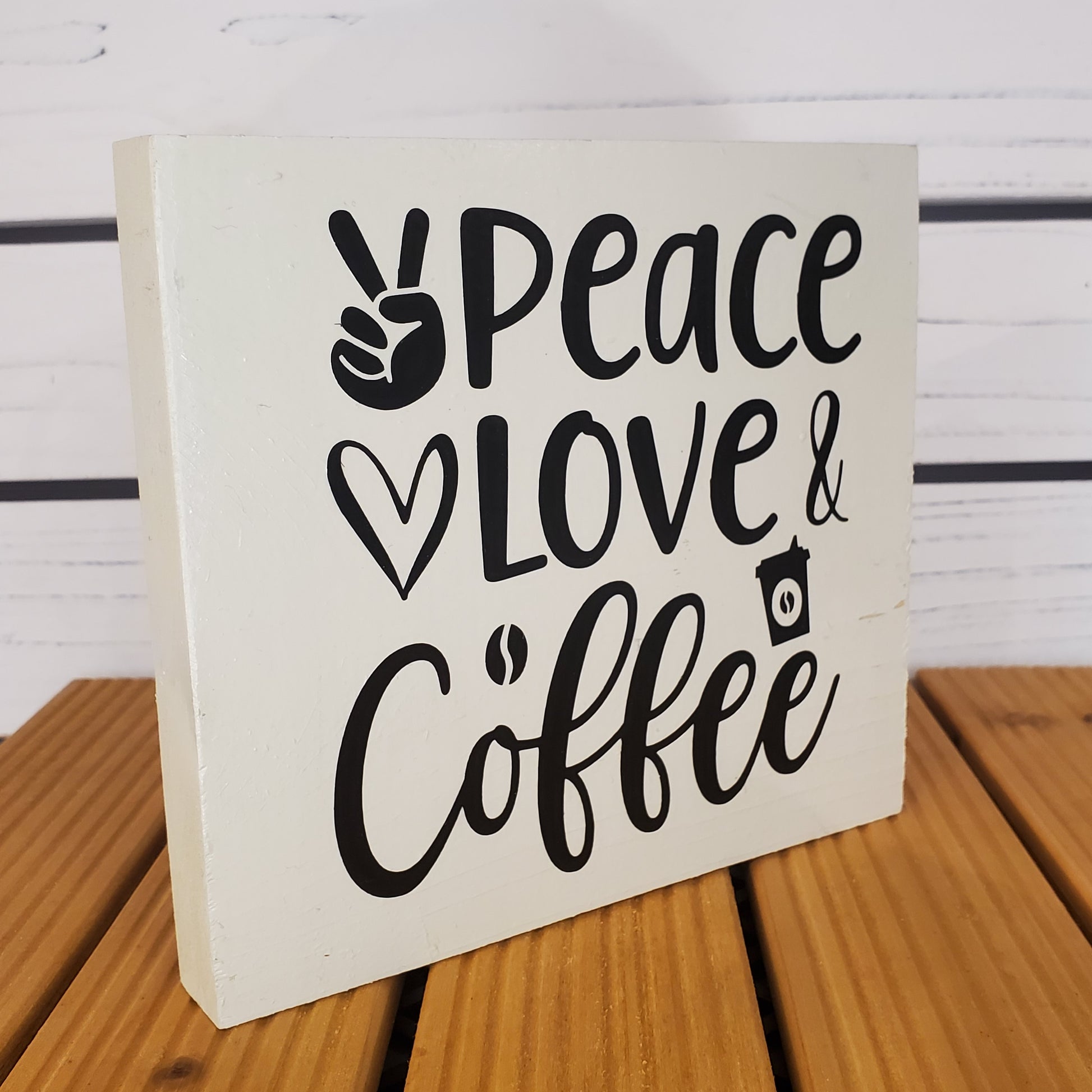 Wooden block with 'Peace & Love & Coffee' text on a wooden surface