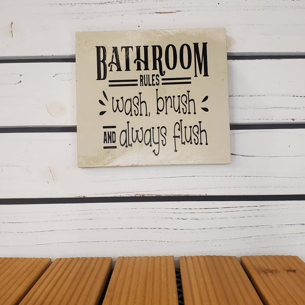 Decorative sign with bathroom rules text on a wooden surface
