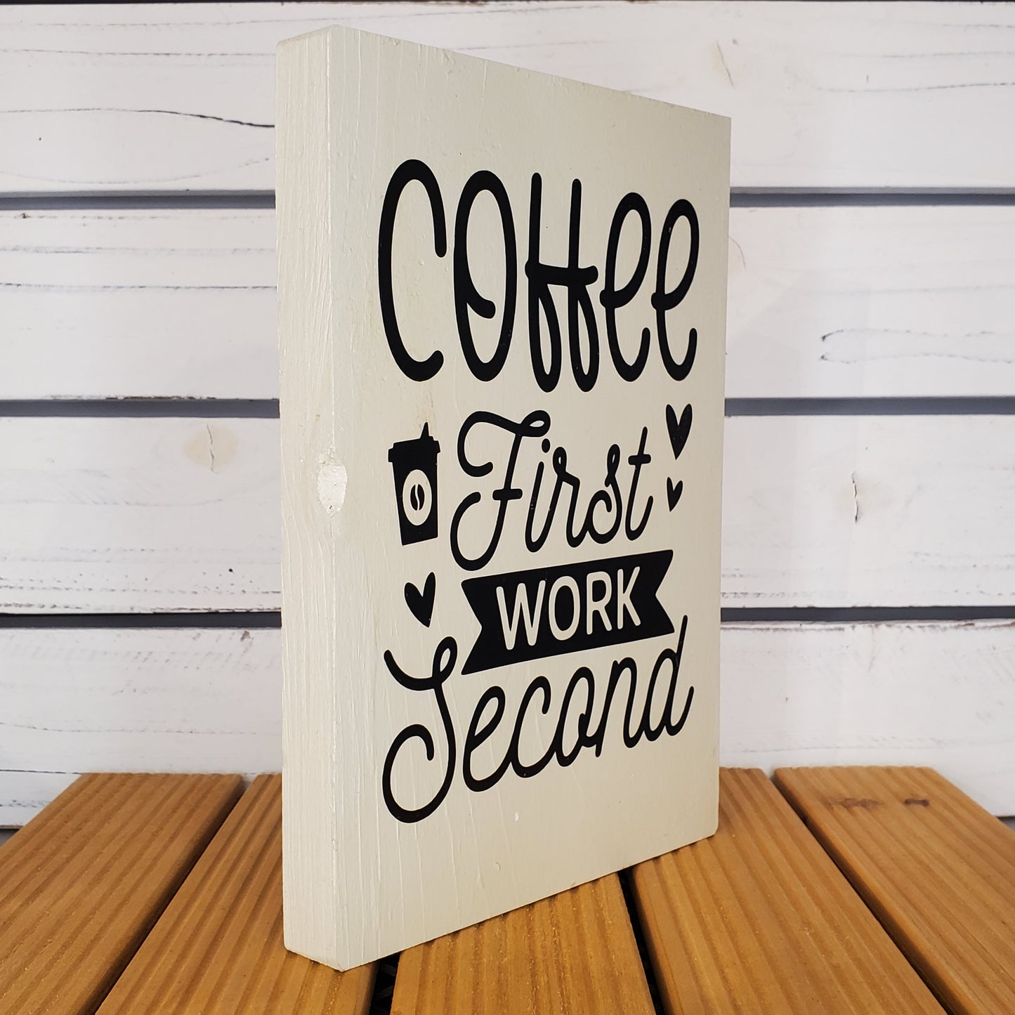 Wooden sign with text 'Coffee First, Work Second' on a wooden surface.