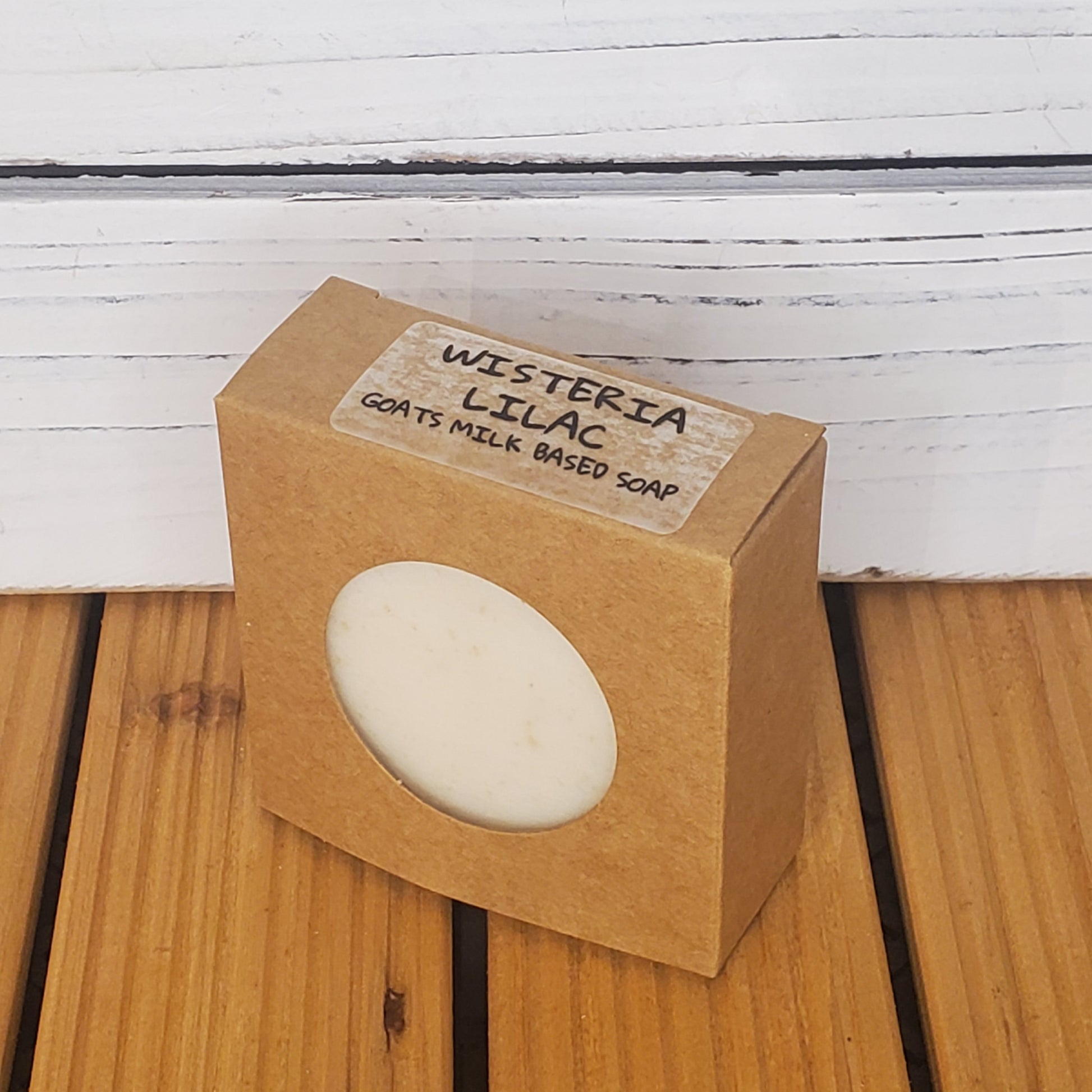 Bar of soap in a brown cardboard box with a label on a wooden surface.