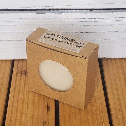 Goat's milk-based soap in a brown cardboard box on a wooden surface.