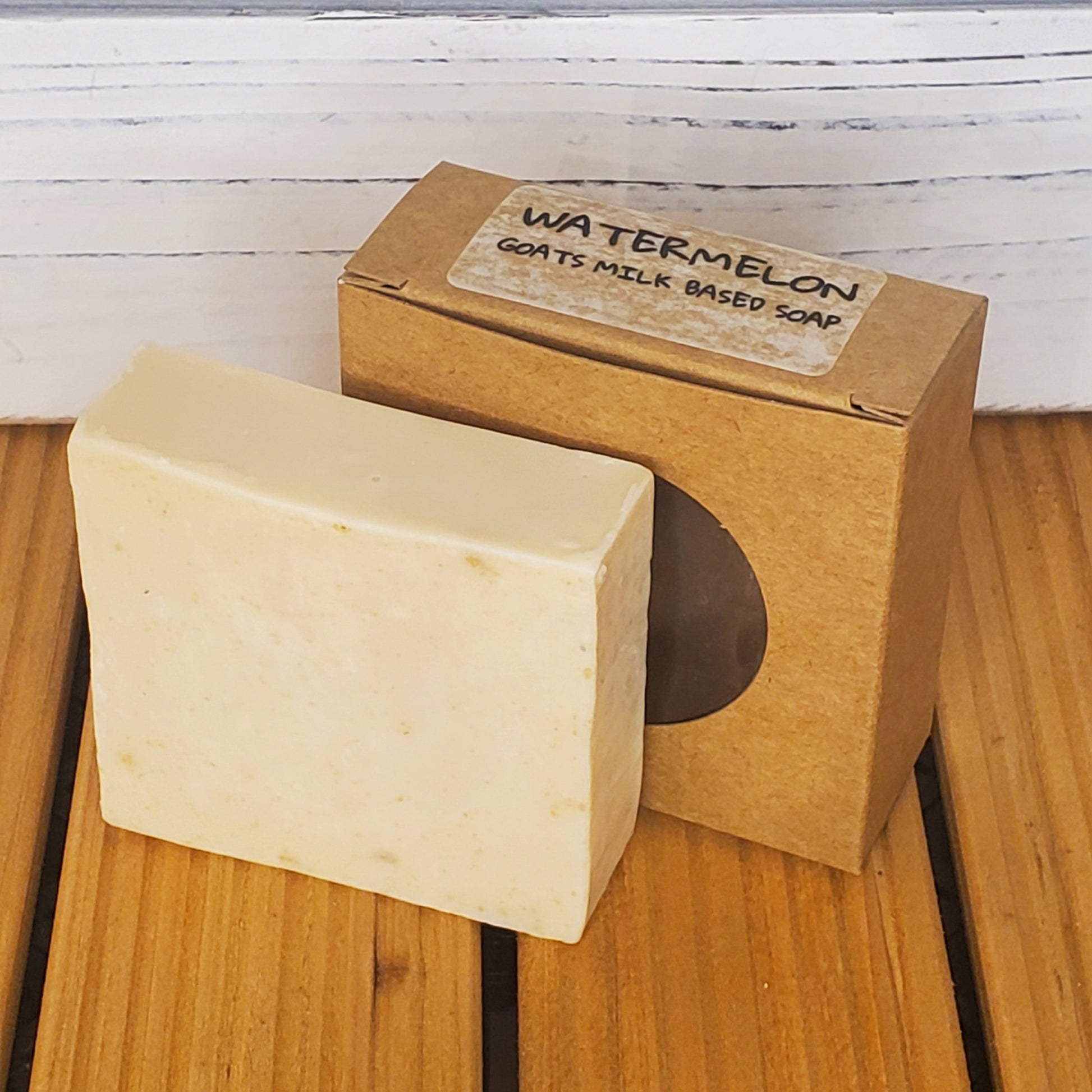 Bar of soap with a cardboard box labeled 'Watermelon' on a wooden surface.