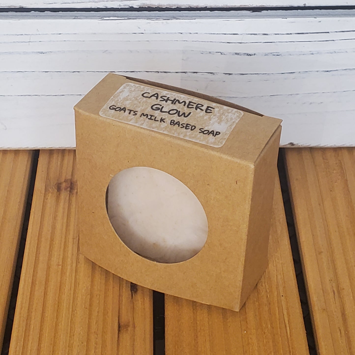 Goats milk-based soap in a brown cardboard box on a wooden surface