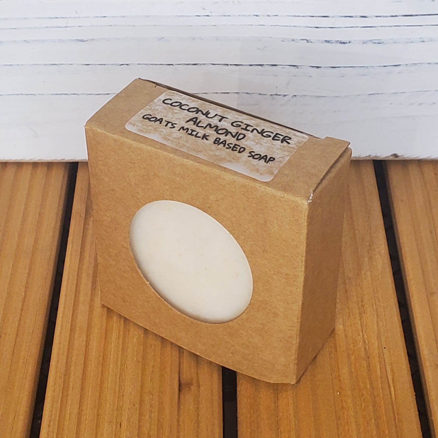 Bar of soap in a brown cardboard box with a label on a wooden surface.