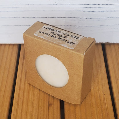 Bar of soap in a brown cardboard box with a label on a wooden surface.