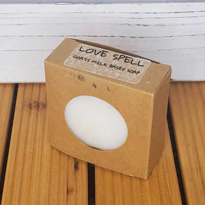 White soap bar in a brown box labeled 'Love Spell' on a wooden surface.