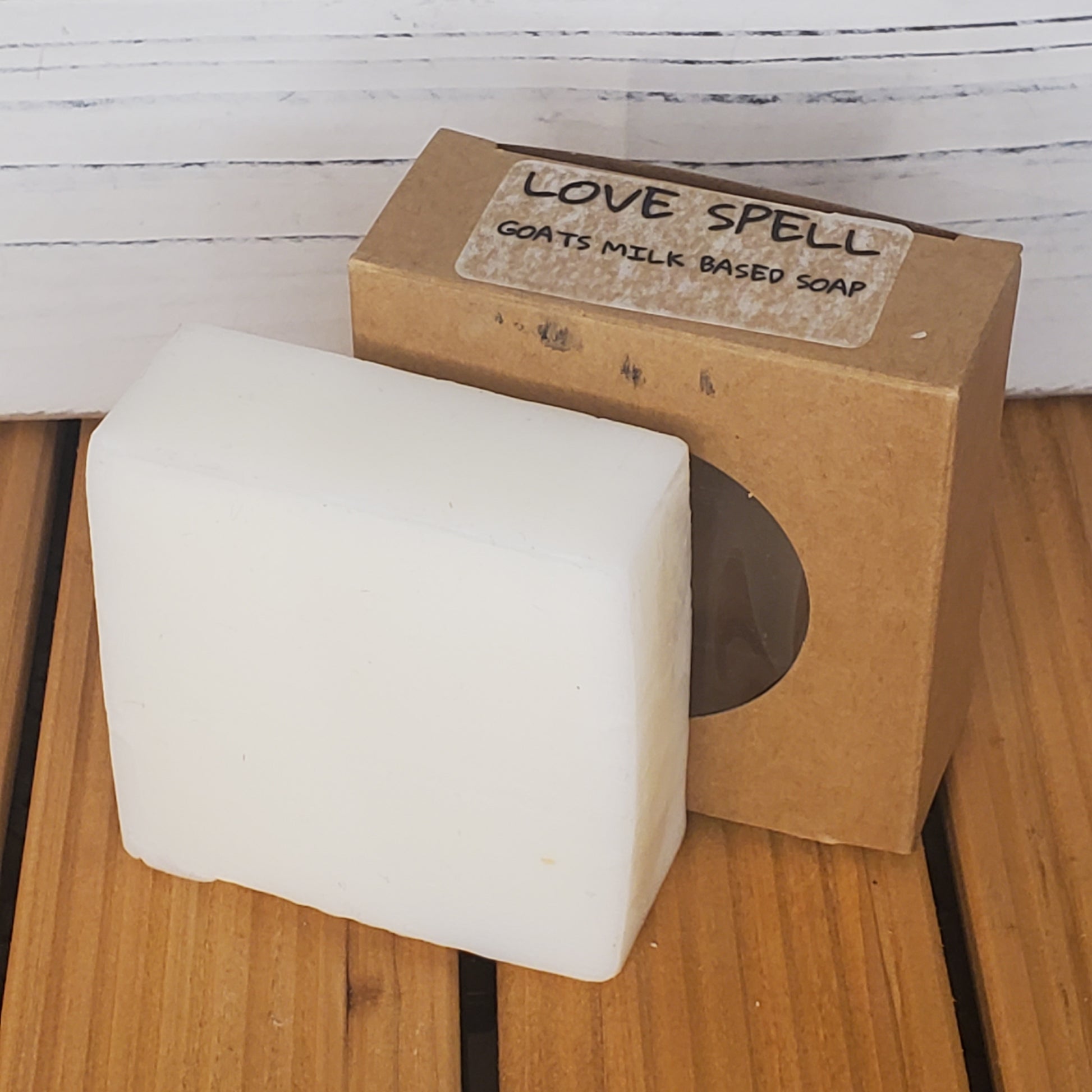 Bar of soap with a cardboard box labeled 'Love Spell' on a wooden surface.