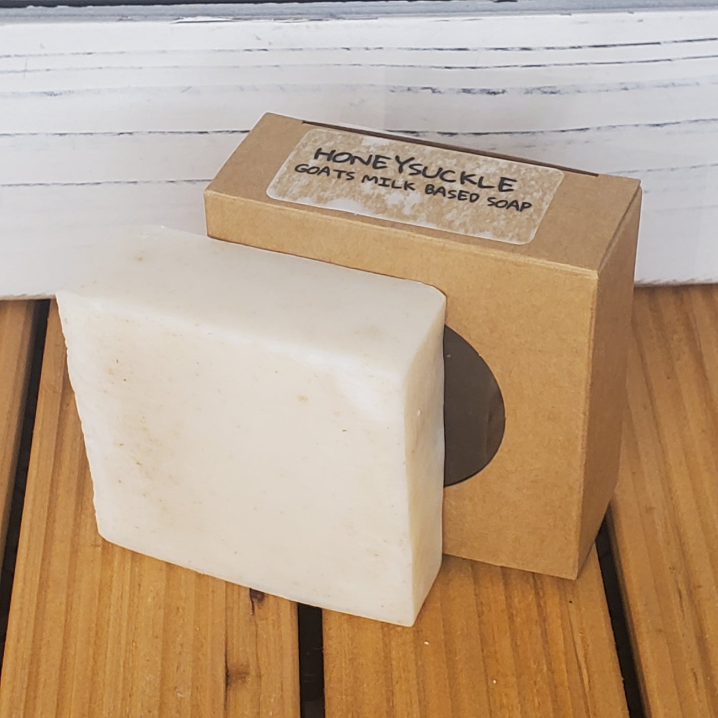 Bar of soap with a cardboard box labeled 'Honeysuckle' on a wooden surface.