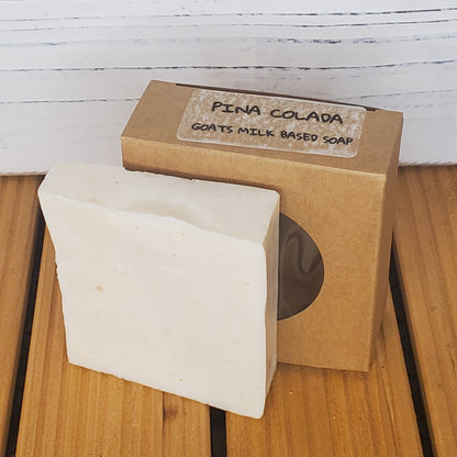Bar of soap with a brown box labeled 'Pina Colada' on a wooden surface.