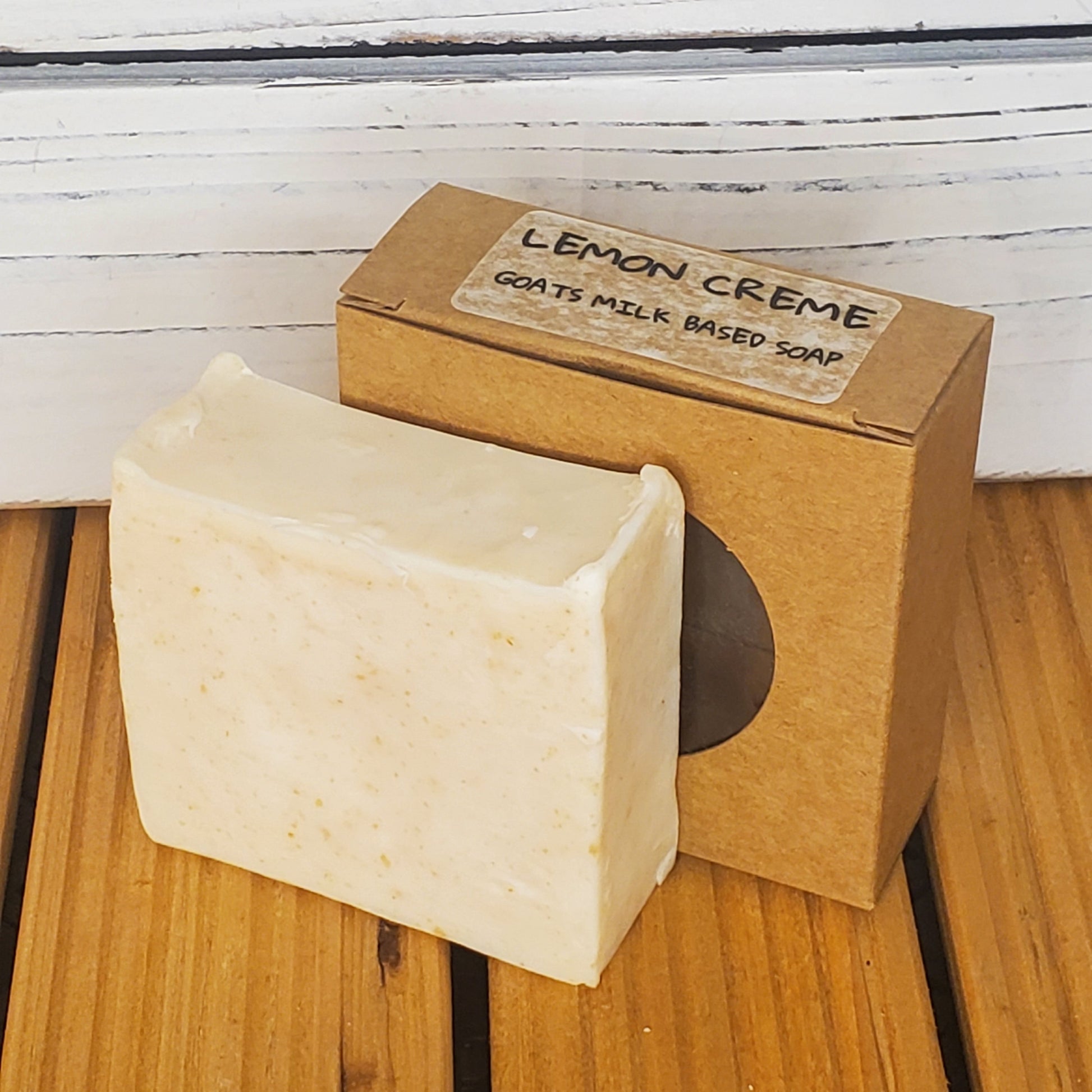 Bar of soap with a brown box labeled 'Lemon Creme' on a wooden surface.