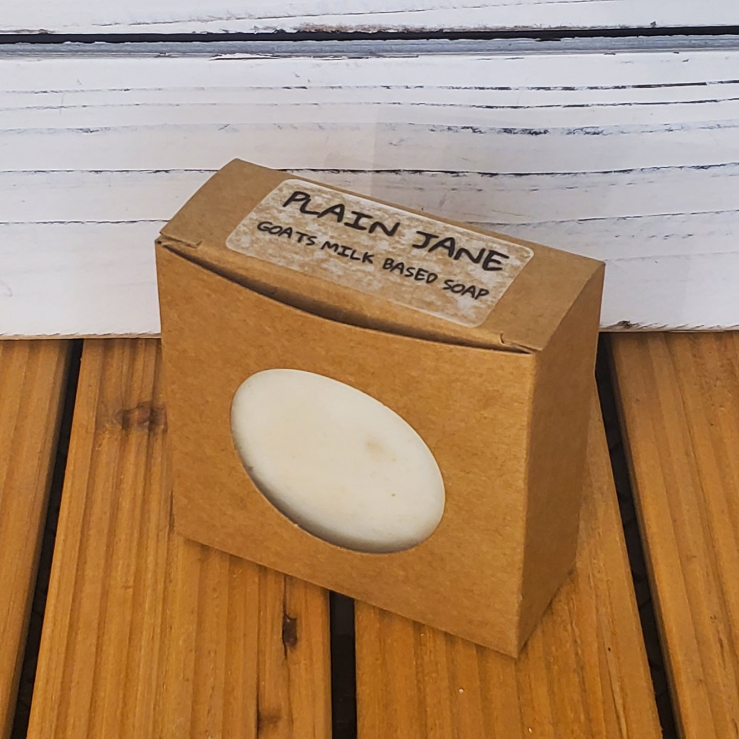 Bar of soap in a cardboard box labeled 'Plain Jane' on a wooden surface.