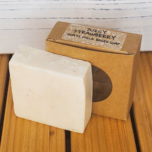 Bar of soap with a cardboard box labeled 'Juicy Strawberry' on a wooden surface.