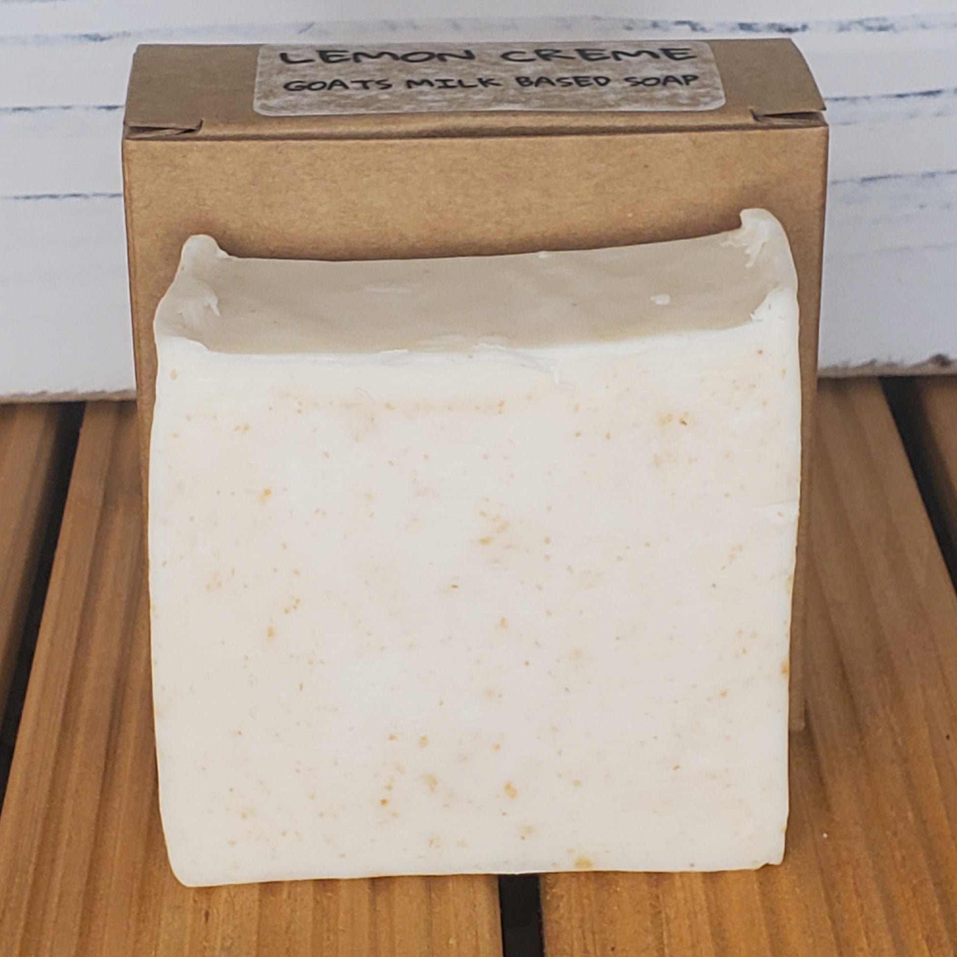 Bar of soap on a wooden surface with a cardboard box labeled 'Lemon Creme'.