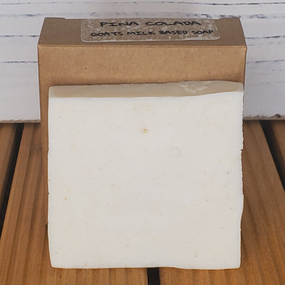 Bar of soap on a wooden block with a visible brand label.