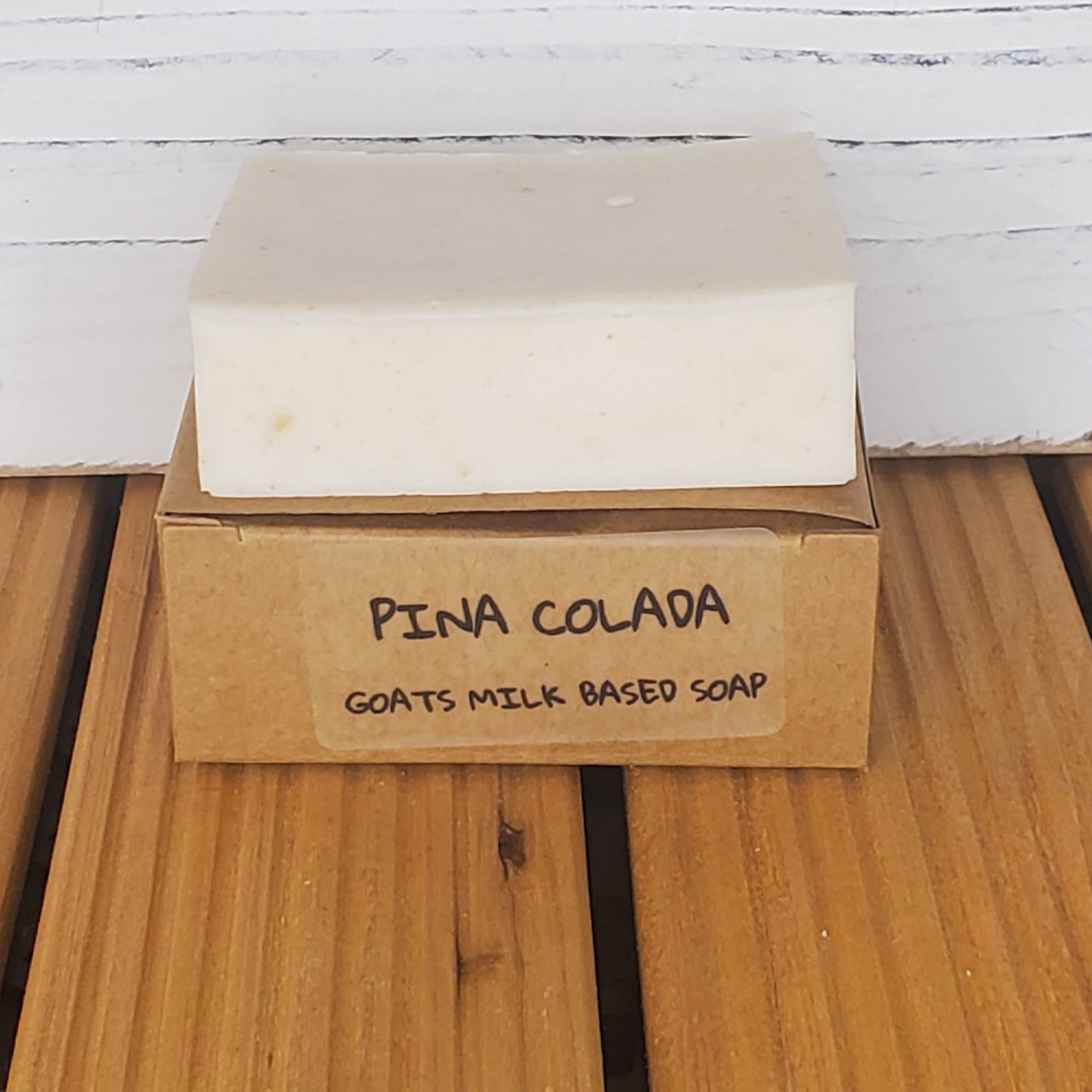Bar of Pina Colada soap with a brown box on a wooden surface