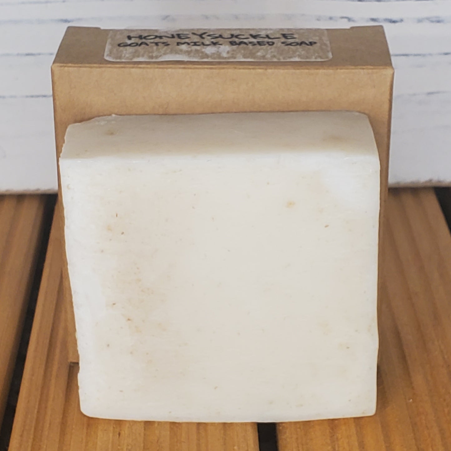Bar of soap on a wooden surface with a cardboard box labeled 'Honeyuckle Soap Co.'