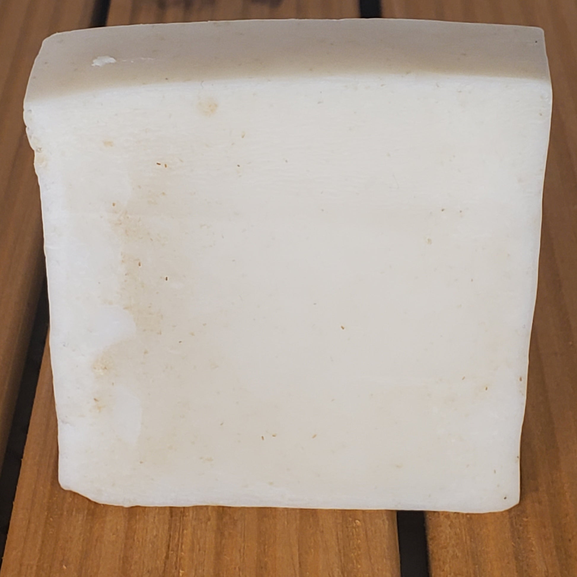 Rectangular block of white soap on a wooden surface