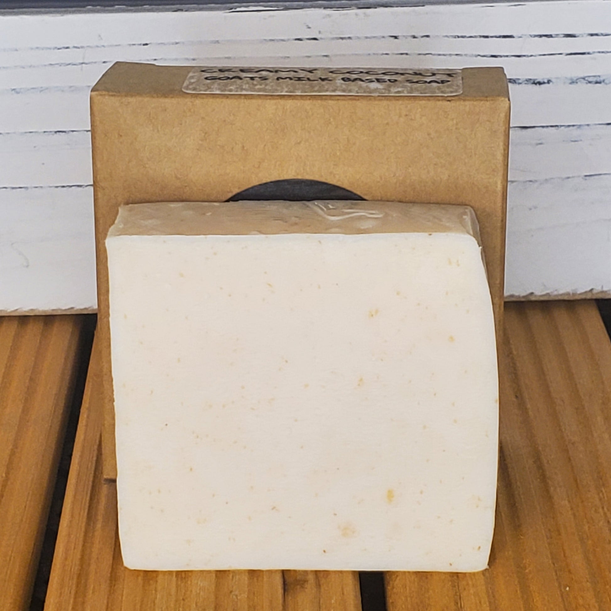 Block of soap on a cardboard box with a wooden surface and white wall in the background