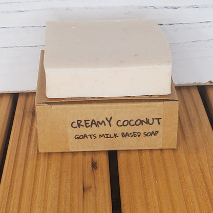 Bar of creamy coconut soap with a cardboard box on a wooden surface
