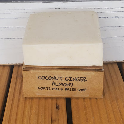 Bar of soap with a cardboard box labeled 'Coconut Ginger Almond Goats Milk' on a wooden surface.